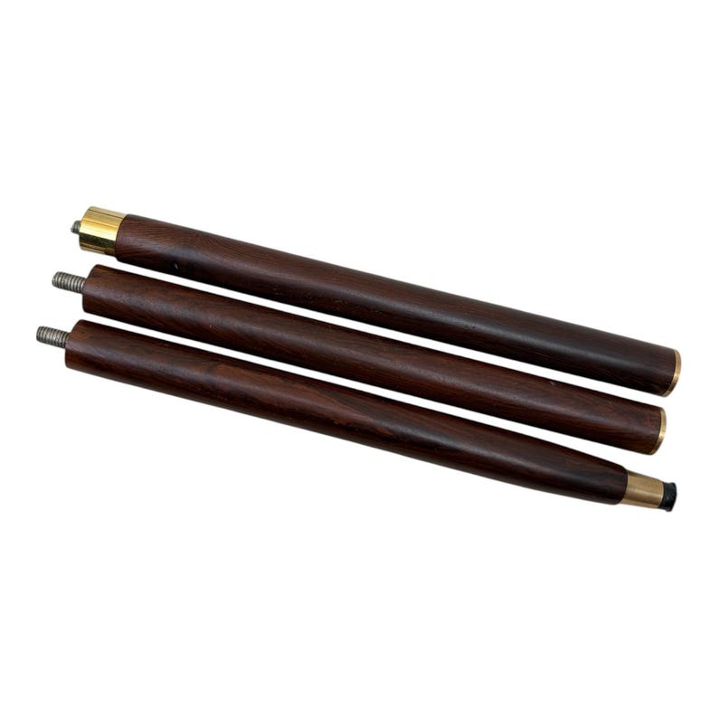 May include: Three-piece wooden cane shaft with brass accents. The dark brown wood is smooth and polished, with a threaded end for assembly. The cane shaft is designed to be assembled into a walking stick.