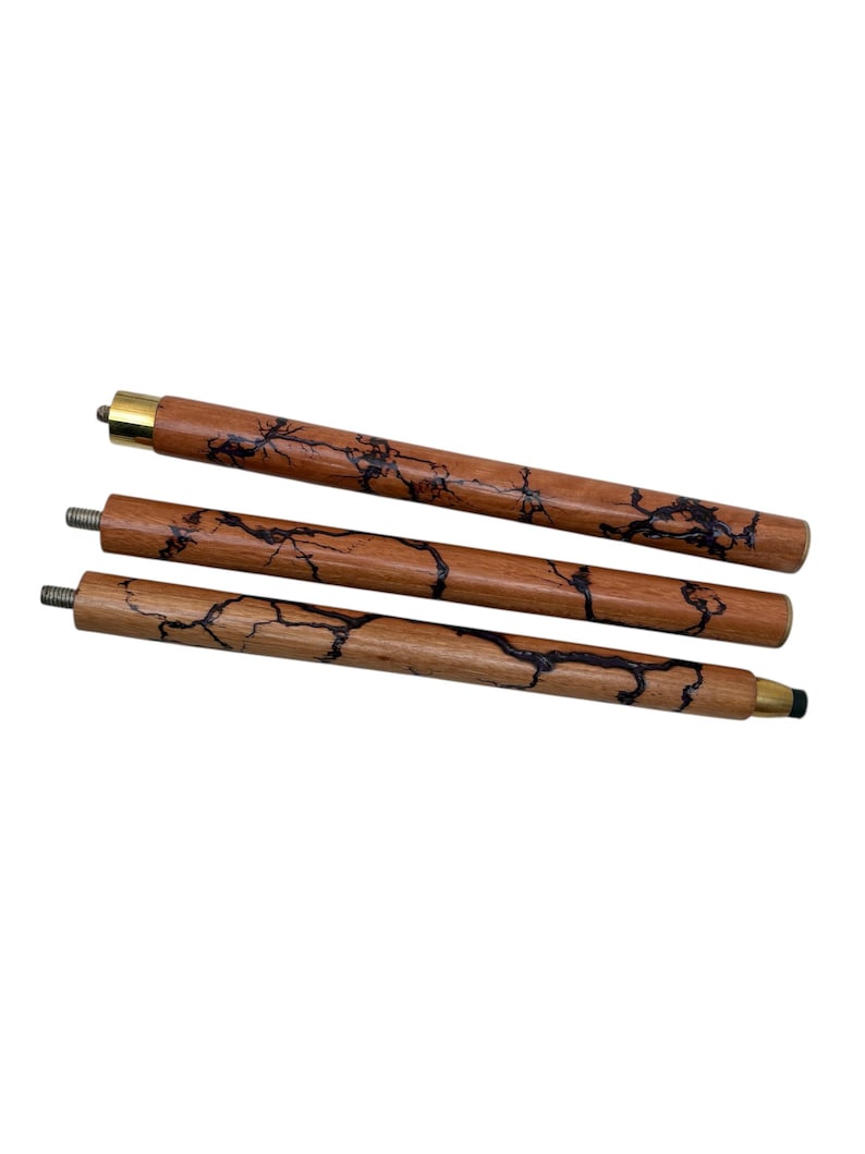 May include: Three wooden walking cane shafts with a dark brown, lightning-like pattern. The shafts are a light brown color and have brass or gold-colored tips. The ends have metal screw threads.