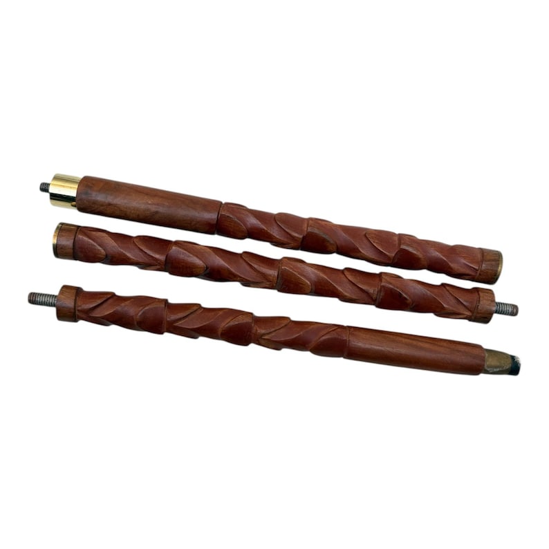 May include: Three-piece wooden walking cane with a dark brown finish. The cane is carved with a spiral design and features brass accents on the top and bottom. The pieces are disassembled, showing the threaded ends for assembly.