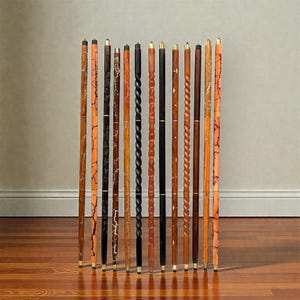 May include: A collection of wooden walking canes with various designs. The canes feature different colors and patterns, including swirls, cracks, and solid colors. Each cane has a brass tip and a handle. The canes are standing upright on a wooden floor.