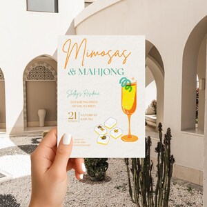Puede incluir: Una tarjeta de invitaci&oacute;n blanca con el texto Mimosas & Mahjong en naranja y verde azulado. El dise&ntilde;o incluye un c&oacute;ctel amarillo en una copa alta con una guarnici&oacute;n verde y cuatro fichas de mahjong blancas. Los detalles incluyen Shelby's Residence, 21 Mahjong Drive, Miami, Florida, 21 de marzo, 11:00 AM e informaci&oacute;n de RSVP.