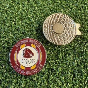 May include: A round metal golf ball marker featuring the Brisbane Broncos logo in maroon, gold, and white with the text Brisbane Broncos Pride of Queensland, alongside a circular silver magnetic hat clip with a textured honeycomb pattern.