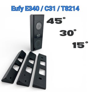 Może przedstawiać: Czarny dzwonek do drzwi wideo Eufy E340 / C31 / T8214 z kamerą i głośnikiem, w zestawie z trzema czarnymi, kątowymi klinami montażowymi. Obraz wyświetla również kąty 45°, 30° i 15°.