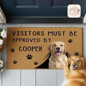 May include: A rectangular doormat with the text "VISITORS MUST BE APPROVED BY COOPER" in black. The mat features a smiling golden retriever and paw prints. The doormat is made of a natural fiber material.
