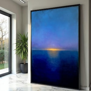 Puede incluir: Gran pintura abstracta enmarcada. La obra presenta un degradado de azules, desde el azul marino oscuro en la parte inferior hasta tonos más claros en la parte superior. Una banda horizontal de amarillo dorado sugiere una puesta de sol o línea de horizonte. El marco es negro.