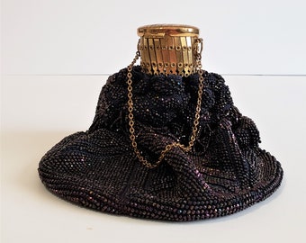 May include: A black beaded evening bag with a gold chain and a gold clasp. The bag is made of small, iridescent beads and has a gathered, ruffled design.