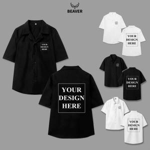 Può includere: Una collezione di camicie button-down a maniche corte in bianco e nero. Ogni camicia presenta il testo "YOUR DESIGN HERE" sul davanti o sul retro. Il logo del marchio "BEAVER" è in alto.