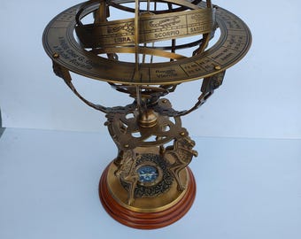 May include: A vintage brass armillary sphere with zodiac signs and text. The sphere is mounted on a wooden base with a compass. The text includes "A PARIS Chez G. Gobitfe" and zodiac signs like "LIBRA" and "SCORPIO".