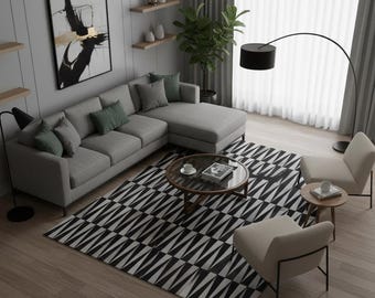 May include: A contemporary living room featuring a grey corner sofa with green cushions, a black and white geometric rug, and a round coffee table. Two armchairs and a floor lamp are also present. An abstract painting adorns the wall.