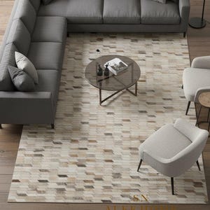 May include: An overhead view of a modern living room with a gray sectional sofa, two armchairs, and a round coffee table. A patterned rug in neutral tones covers the floor. A black floor lamp is positioned near the sofa.