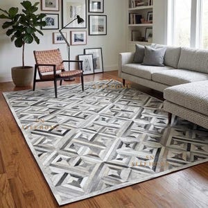 May include: A rectangular area rug featuring a geometric patchwork pattern in shades of gray, white, and black. The rug displays a repeating design of interconnected squares and rectangles, with the text SN ALEE HOME visible on the surface.