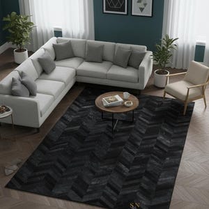 Peut inclure: Un salon moderne avec un canapé d'angle gris clair, une table basse en bois et un tapis noir à chevrons. La pièce est décorée de plantes en pot, d'œuvres d'art encadrées et d'un fauteuil beige.
