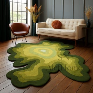 May include: A green and yellow area rug with an organic, layered design. The rug features a series of concentric shapes in varying shades of green and yellow, creating a topographic effect. The rug is on a hardwood floor.