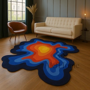 May include: An abstract rug with a layered design in a living room. The rug features concentric shapes in shades of blue, orange, and yellow. The rug's unique shape adds a modern touch to the room's decor. The rug is a striking focal point.