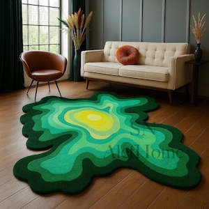 May include: A unique, abstract rug in shades of green and yellow, resembling a topographical map. The rug's irregular shape and layered design create a modern, artistic statement. The rug is placed on a wooden floor in a living room setting.