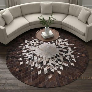 Peut inclure: Un canapé beige incurvé avec des coussins est placé au-dessus d'un tapis rond avec un motif géométrique marron et blanc. Une petite table basse ronde en bois avec un vase et des livres est au centre.