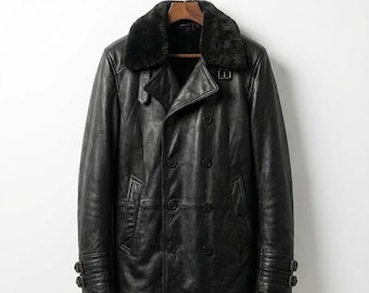 May include: Black leather jacket with a double-breasted design, featuring a faux fur collar and buckle details on the sleeves. The jacket is hanging on a wooden hanger.