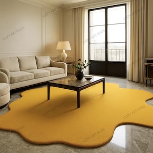 May include: A mustard yellow, organically shaped rug in a living room setting. The rug is the focal point, with a sofa, armchair, and coffee table arranged around it. The room has neutral walls and large windows.