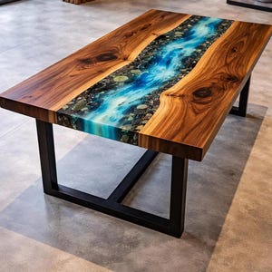 Könnte beinhalten: Ein rechteckiger Couchtisch mit zwei dicken, naturbelassenen braunen Holzplatten mit Baumkante, die durch eine mittige, flussartige Einlage aus blauem Harz mit kleinen grauen und braunen Steinen getrennt und von einem schwarzen Metallgestell getragen werden.