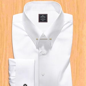 Peut inclure: Une chemise blanche avec un motif texturé, une épingle de col et des boutons de manchette. La chemise a un design classique avec une fermeture boutonnée et une étiquette "PANACHE".