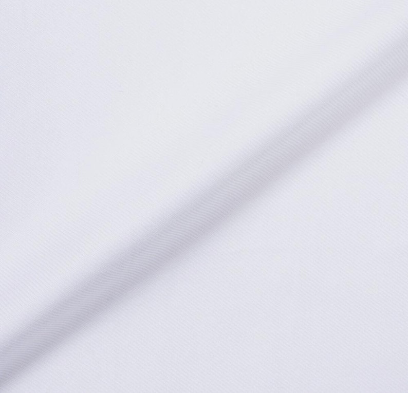 May include: Close-up of white fabric with a diagonal fold. The fabric has a subtle ribbed texture, creating a play of light and shadow across its surface. The material appears to be smooth and tightly woven.