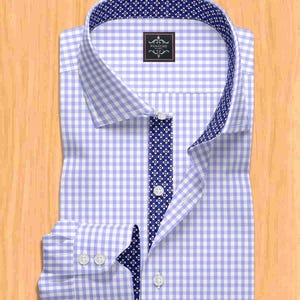 Può includere: Una camicia a quadretti vichy azzurra e bianca con un motivo floreale blu navy a contrasto sul colletto e l'abbottonatura. La camicia ha un colletto classico e polsini con bottoni. Il marchio "PANACHE" è visualizzato su una piccola etichetta.