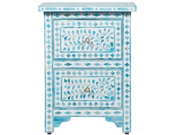 May include: A two-drawer nightstand with a light blue and white floral design. The nightstand features a mosaic pattern with diamond and floral accents. Each drawer has a round silver knob.
