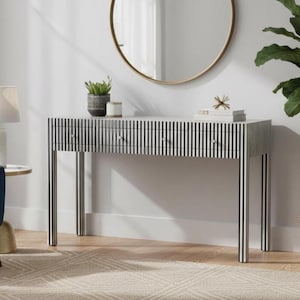 May include: A rectangular console table featuring a black and white vertical striped pattern across its surface and four legs. The table includes three drawers with small round silver knobs, providing a structured and linear appearance.