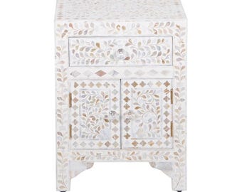 May include: A white bedside table with a drawer and cabinet doors. The table is decorated with a floral pattern in shades of white, beige, and gray. The table measures approximately 24 inches tall, 16 inches wide, and 14 inches deep.