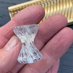 May include: A clear glass cabinet knob with a textured, ribbed design.