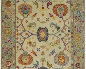 May include: A rectangular area rug with a beige central field and a detailed floral pattern in shades of orange, blue, yellow, and purple. The rug has a gray border with additional floral motifs. The rug is designed for home decor.