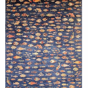 Puede incluir: Una alfombra rectangular grande con un fondo azul oscuro. La alfombra está densamente cubierta con varios diseños de peces coloridos en tonos naranja, amarillo, blanco y marrón. Los peces varían en tamaño y patrón, creando un tema acuático animado.