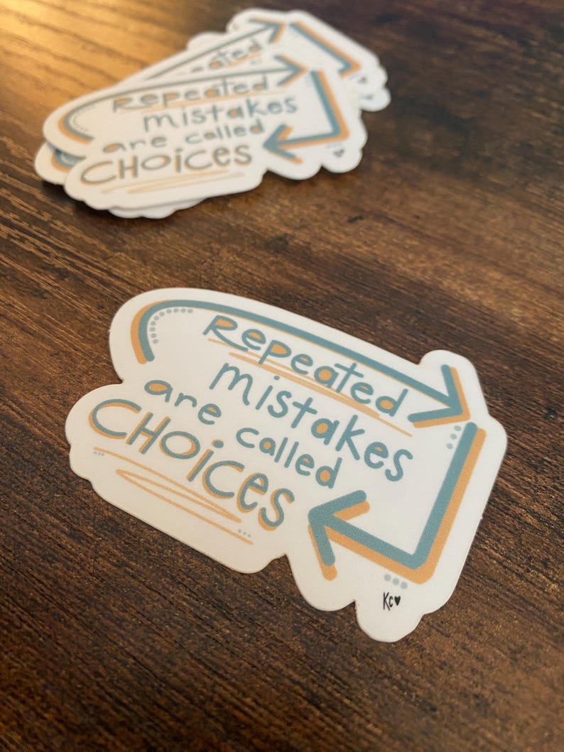 K&ouml;nnte beinhalten: Wei&szlig;er Aufkleber mit dem Text "Repeated mistakes are called CHOICES" in einer verspielten Schriftart. Der Text ist von einem hellblauen und orangefarbenen Design umgeben. Mehrere Aufkleber sind auf einer Holzoberfl&auml;che zu sehen.