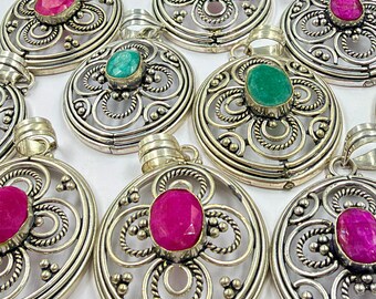 May include: A collection of circular silver pendants featuring intricate wirework and filigree patterns. Each pendant is centered with a single oval-shaped gemstone, alternating between vibrant fuchsia pink and deep emerald green faceted stones.