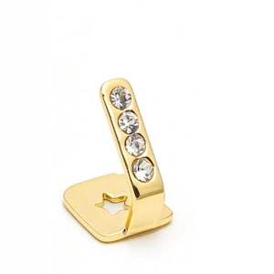 May include: A gold-toned metal accessory featuring a flat square base with a star-shaped cutout and an angled upright arm. The upright arm is embellished with four clear, round, faceted crystals arranged in a vertical line along its surface.