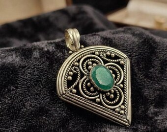 May include: A silver pendant featuring a central oval-cut green gemstone. The metalwork displays intricate filigree, twisted rope borders, and small spherical accents arranged in a fan-shaped design with a prominent bail at the top.