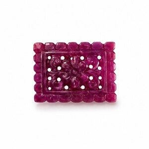 Peut inclure: Une plaque rectangulaire en pierre précieuse sculptée de couleur magenta profond, présentant un motif floral ajouré complexe au centre. La pièce est encadrée par une bordure festonnée et facettée, avec une finition polie et une teinte riche.
