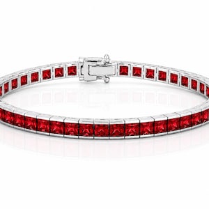 Può includere: Un bracciale tennis color argento caratterizzato da una fila continua di pietre rosse a taglio quadrato incastonate in una montatura metallica. Il bracciale include una chiusura a cassetta sicura che unisce le due estremità.