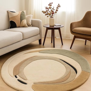 Pode incluir: Um tapete redondo com um campo central creme e um design em espiral em tons de bege, castanho e verde. O tapete está colocado sobre um chão de madeira clara, complementando os tons neutros da decoração da divisão. O design do tapete adiciona um toque moderno.