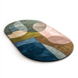 May include: An oval-shaped rug with a modern geometric design. The rug features a color palette of blue, green, pink, and brown. The design includes overlapping shapes and patterns. The text "The Rug Expert" is visible on the rug.