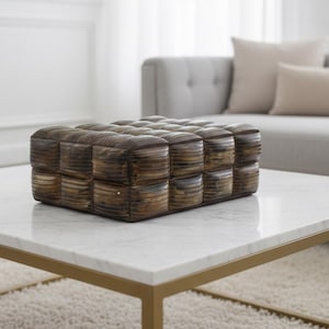May include: A rectangular, woven brown decorative box with a textured surface. The box is made of natural materials and sits on a white marble coffee table with a gold-colored metal frame. The background includes a gray sofa and neutral-toned pillows.