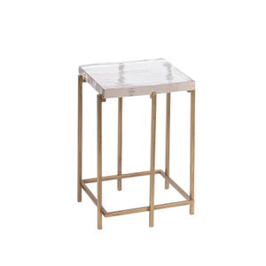 May include: A square side table with a clear, textured top and a gold-colored metal frame. The table has four legs and a lower support structure, creating a modern and elegant design. The table is suitable for a living room or bedroom.