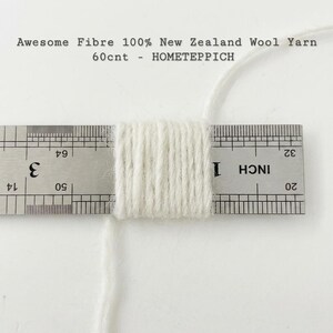 May include: A close-up of a bundle of white yarn, measured with a ruler. The ruler shows measurements in inches. Text at the top reads "Awesome Fibre 100% New Zealand Wool Yarn 60cnt - HOMETEPPICH."