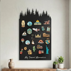 May include: A black wall-mounted display board with a forest silhouette at the top. It features colorful travel-themed magnets, including landmarks, vehicles, and a cactus. The text "My Travel Memories" is at the bottom.