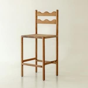 K&ouml;nnte beinhalten: Ein hellbrauner Barhocker aus Holz mit quadratischer Sitzfl&auml;che und einer hohen R&uuml;ckenlehne mit zwei horizontalen Streben. Jede Strebe hat eine markante, wellenf&ouml;rmige Oberkante. Der Hocker verf&uuml;gt &uuml;ber vier gerade Beine und Fu&szlig;st&uuml;tzen.