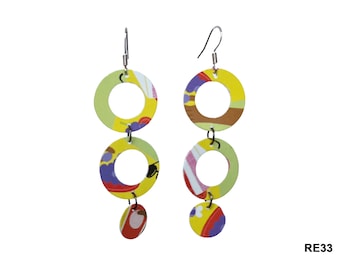 May include: A pair of colorful earrings with three circles and a small circle at the bottom. The circles are made of fabric with a yellow, green, red, and purple pattern. The earrings have silver hooks.