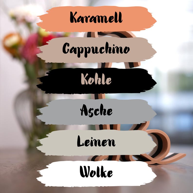 K&ouml;nnte beinhalten: Eine Farbpalette mit sechs Farbfeldern mit den Bezeichnungen "Karamell", "Cappuchino", "Kohle", "Asche", "Leinen" und "Wolke". Die Farben sind Pfirsich, Beige, Schwarz, Grau, Hellbeige und Wei&szlig;. Im Hintergrund ein dekoratives Holzelement.