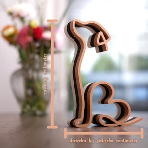 K&ouml;nnte beinhalten: Eine mehrschichtige Holzskulptur eines Hundes mit herzf&ouml;rmigem K&ouml;rper und gebogenem Schwanz. Die Skulptur ist etwa 20 cm hoch und 13-17 cm breit. Der Text auf dem Bild lautet "zwanzig Zentimeter" und "dreizehn bis siebzehn Zentimeter".