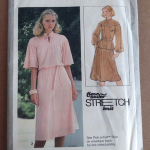 May include: A sewing pattern for a dress, Simplicity pattern number 8514, size O (12, 14, and 16). The pattern is for a dress with a tie at the neck and a belt. The pattern is for stretch knit fabric. The pattern is available in sizes 6-10, 8-12, 10-14, and 12-16.