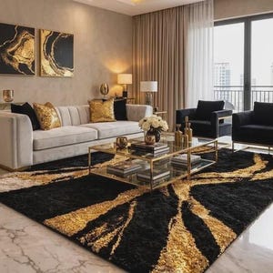 Könnte beinhalten: Ein modernes Wohnzimmer mit neutraler Farbpalette. Es verfügt über ein hellgraues Sofa mit goldenen Akzentkissen, einen schwarz-gold gemusterten Teppich und zwei schwarze Sessel. Gold gerahmte Kunstwerke und ein Glastisch vervollständigen den Look.